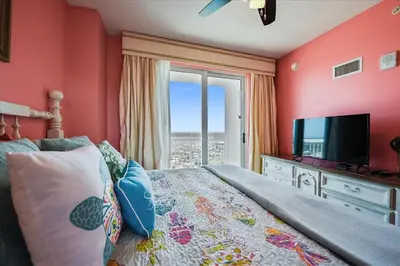 a bedroom with a bed with a television and a window at 1909 Seychelles in Panama City Beach
