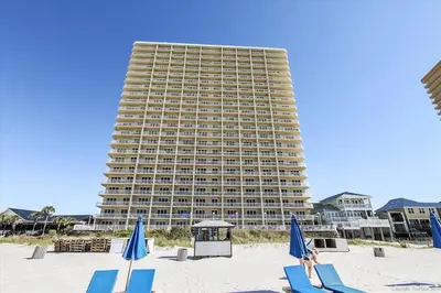 a large building on the beach with chairs and umbrellas at 1909 Seychelles in Panama City Beach