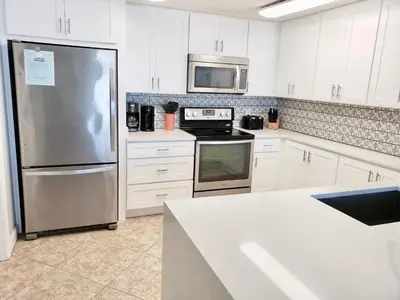 a kitchen with white cabinets and a stainless steel refrigerator at 1409-Seychelles in Panama City Beach