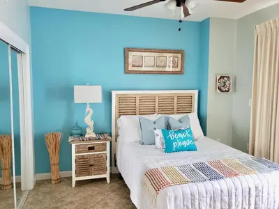 a bedroom with a bed with a blue wall at 1409-Seychelles in Panama City Beach