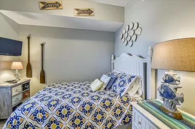 a bedroom with a bed with a blue and white comforter at 1409-Seychelles in Panama City Beach