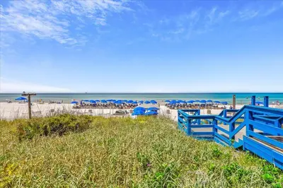 a beach with blue fences and umbrellas and the ocean at 1409-Seychelles in Panama City Beach