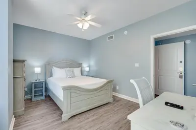 a bedroom with a white bed and a ceiling fan at 305 Marisol in Panama City Beach