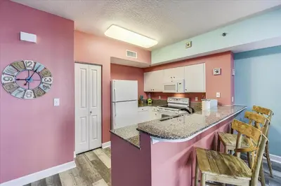 a kitchen with pink walls and a counter with chairs at 225-Shores Of Panama in Panama City Beach