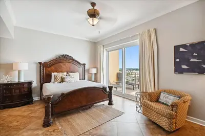 a bedroom with a bed and a chair and a window at 701 Sterling Beach in Panama City Beach