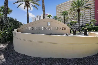 a sign for the beginning of a building with palm trees at 701 Sterling Beach in Panama City Beach