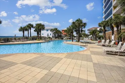 a swimming pool with chairs and palm trees in a resort at 701 Sterling Beach in Panama City Beach
