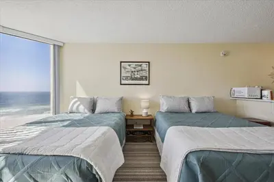 two beds in a room with a view of the ocean at 721 Top Of The Gulf in Panama City Beach