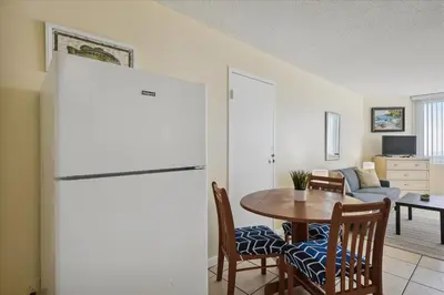 a kitchen and dining room with a table and a refrigerator at 721 Top Of The Gulf in Panama City Beach