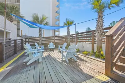a deck with blue chairs and a hammock and palm trees at 721 Top Of The Gulf in Panama City Beach