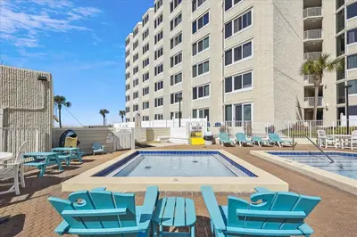 a swimming pool with blue chairs and a building at 721 Top Of The Gulf in Panama City Beach