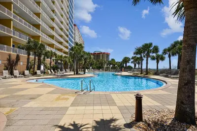 a swimming pool with palm trees and a building at 1504 Sterling Beach in Panama City Beach