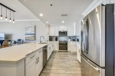 a kitchen with white cabinets and a stainless steel refrigerator at 302 Sterling Beach in Panama City Beach