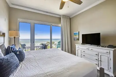 a bedroom with a bed with a television and a balcony at 302 Sterling Beach in Panama City Beach