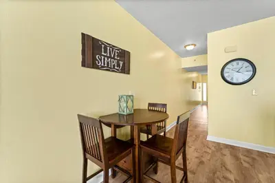 a dining room with a table and chairs and a clock at Shores of Panama #1027 by Nautical Properties in Panama City Beach