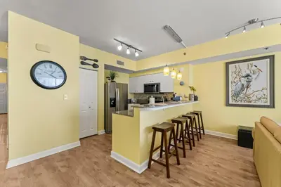 a kitchen with yellow walls and a bar with stools at Shores of Panama #1027 by Nautical Properties in Panama City Beach