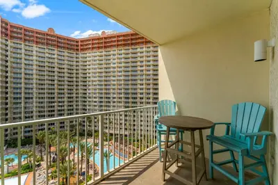a balcony with two chairs and a table and a building at Shores of Panama #1027 by Nautical Properties in Panama City Beach