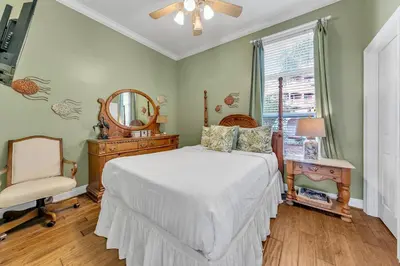 a bedroom with a bed and a chair and a mirror at Blue Turtle Beach House by Emerald Coast Retreats in Panama City Beach