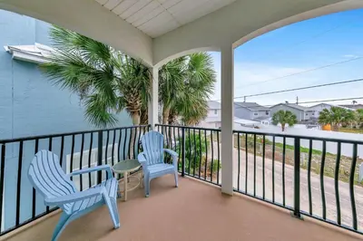 a balcony with two blue chairs and a table at Blue Turtle Beach House by Emerald Coast Retreats in Panama City Beach