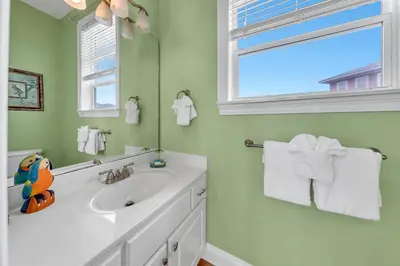 a white bathroom with a sink and a window at Blue Turtle Beach House by Emerald Coast Retreats in Panama City Beach