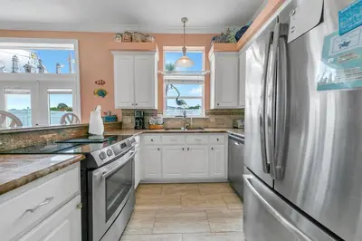 a kitchen with white cabinets and a stainless steel refrigerator at Blue Turtle Beach House by Emerald Coast Retreats in Panama City Beach