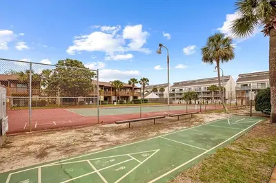 a tennis court with two benches on a tennis court at Portside 2SG- Seabreeze Townhome by Emerald Coast Retreats in Panama City Beach