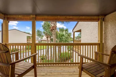 two chairs on a porch with a view of a palm tree at Portside 2SG- Seabreeze Townhome by Emerald Coast Retreats in Panama City Beach