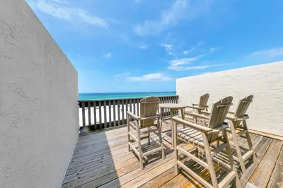 a deck with chairs and the ocean in the background at Largo Mar 106 by Emerald Coast Retreats in Panama City Beach