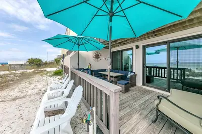 a porch with chairs and umbrellas on the beach at Largo Mar 106 by Emerald Coast Retreats in Panama City Beach