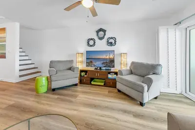 a living room with two chairs and a tv at Largo Mar 106 by Emerald Coast Retreats in Panama City Beach