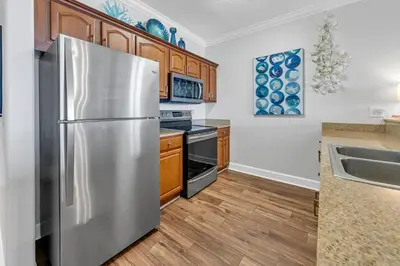 a kitchen with a stainless steel refrigerator and wooden cabinets at Ocean Reef 1204 in Panama City Beach