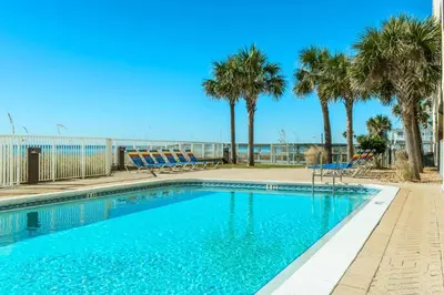 a swimming pool with palm trees and chairs at Ocean Reef 1204 in Panama City Beach