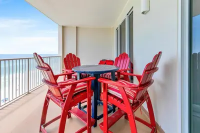 a blue table and four red chairs on a balcony at Ocean Reef 1204 in Panama City Beach