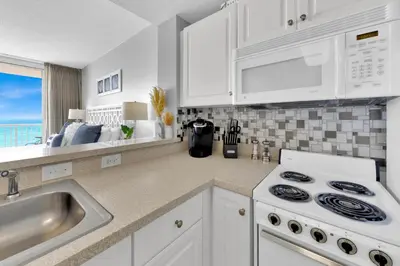 a kitchen with white cabinets and a stove and a sink at Beachfront Unit-Majestic Beach Resort in Panama City Beach