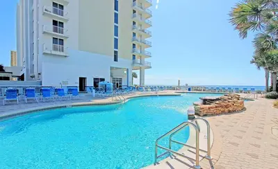 a swimming pool with blue chairs and a building at Beachfront Unit-Majestic Beach Resort in Panama City Beach