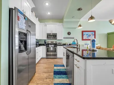 a kitchen with white cabinets and stainless steel appliances at Sunset Sanctuary by Emerald Coast Retreats in Panama City Beach