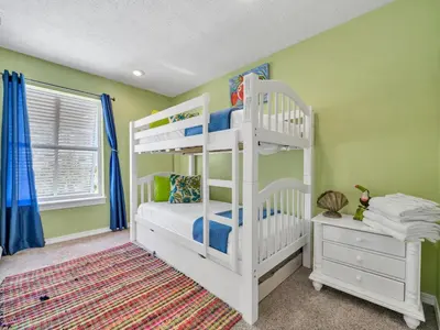 a white bedroom with two bunk beds and a window at Sunset Sanctuary by Emerald Coast Retreats in Panama City Beach