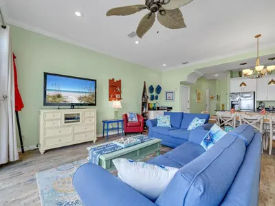 a living room with blue couches and a flat screen tv at Sunset Sanctuary by Emerald Coast Retreats in Panama City Beach