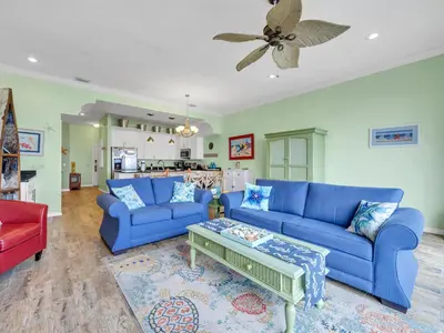a living room with blue couches and a table at Sunset Sanctuary by Emerald Coast Retreats in Panama City Beach