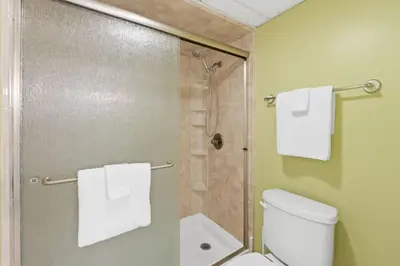 a bathroom with a shower and a toilet and towels at Edgewater Golf Villa 605 in Panama City Beach