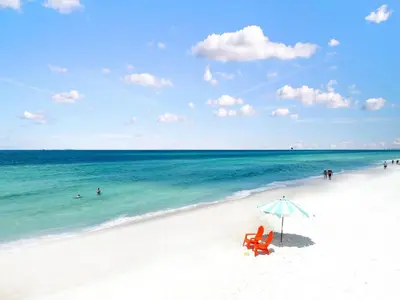 a beach with two chairs and an umbrella and the ocean at Southwinds Unit D3 in Panama City Beach