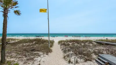a flag on a beach with a palm tree at Villas Bahama West 106 in Panama City Beach