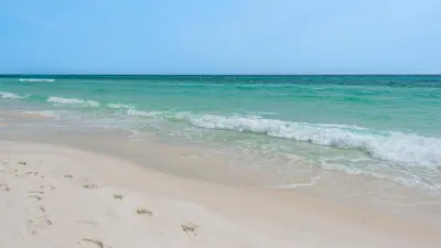 a beach with the ocean and some footprints in the sand at Villas Bahama West 106 in Panama City Beach