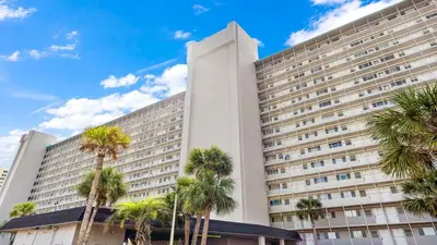 a large building with palm trees in front of it at The Summit 927 in Panama City Beach