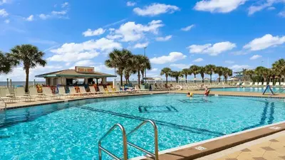 a large swimming pool with palm trees and a beach at The Summit 927 in Panama City Beach