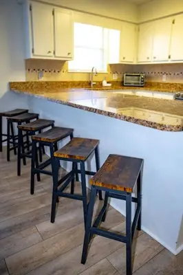 a row of wooden stools at a counter in a kitchen at Tropical Oasis, Tiki Bar, Pool, Mini Golf, Hot Tub in Panama City Beach