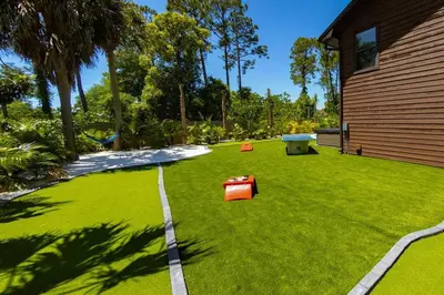 a yard with green grass and a house at Tropical Oasis, Tiki Bar, Pool, Mini Golf, Hot Tub in Panama City Beach