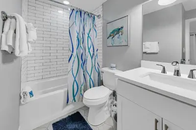 a bathroom with a white toilet and a sink at Tidewater 1802 in Panama City Beach