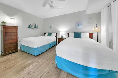 a bedroom with two beds and a dresser at Tidewater 1802 in Panama City Beach