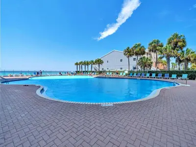 a large swimming pool next to a beach with palm trees at Tidewater 1802 in Panama City Beach
